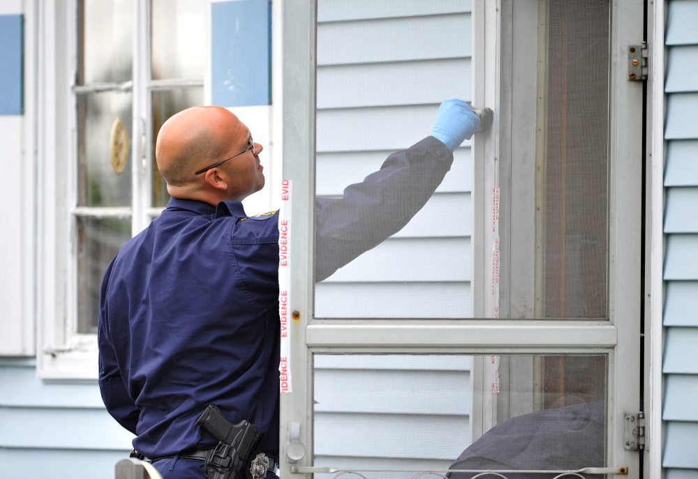 An investigator with the Maine State Police Major Crimes Unit dusts for fingerprints at the residence of Aurele Fecteau, 92, who was found dead in his home on Brooklyn Street in Waterville on Friday.