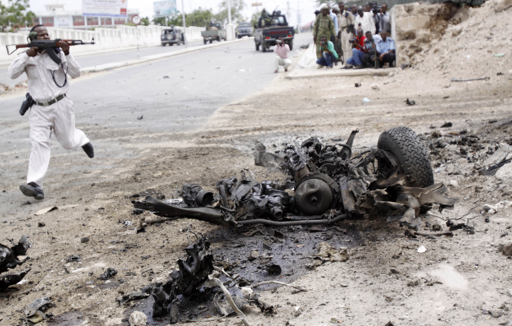 A Somali soldier runs past the wreckage from a car bomb during an attack on the parliament building on Saturday in Mogadishu, Somalia. Among those reported killed are six attackers and a soldier who tried to stop a suicide bomber from entering the building.