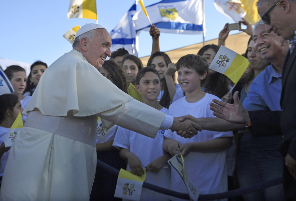 Pope Francis greets Israeli children in Jerusalem on Sunday. The pontiff took a plunge into Mideast politics while on his Holy Land pilgrimage, receiving an acceptance from the Israeli and Palestinian presidents to visit him at the Vatican next month to discuss peace efforts.