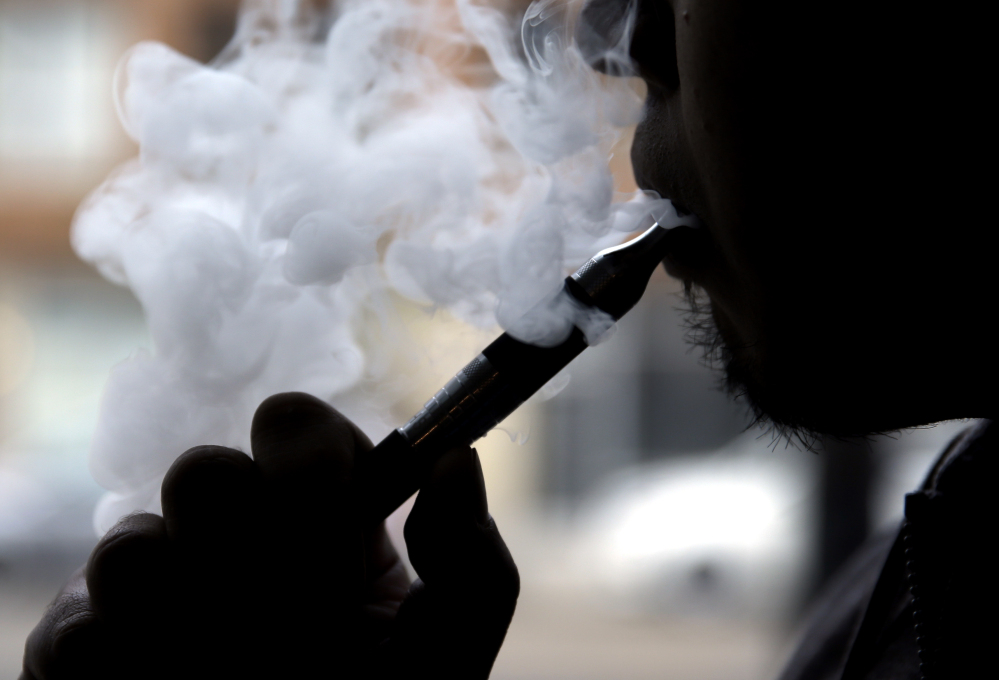In this April 23, 2014 file photo, an electronic cigarette is demonstrated in Chicago. Some makers of the liquid nicotine used in electronic cigarettes are using notable brand names like Thin Mint, Tootsie Roll and Cinnamon Toast Crunch to sell their wares.
