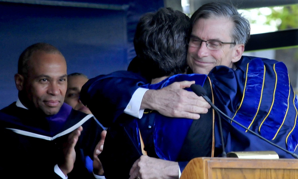 Retiring Colby College President William D. Adams hugs Dean of Faculty Lori Kletcher after receiving an honorary Doctor of Letters degree during his final commencement Sunday. At left is Massachusetts Gov. Deval Patrick.