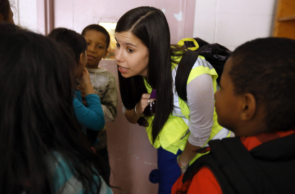 Allyson Trenteseaux, a Walking School Bus program manager, center, speaks with grade school children as they prepare to walk home from school as a group, in Providence, R.I.