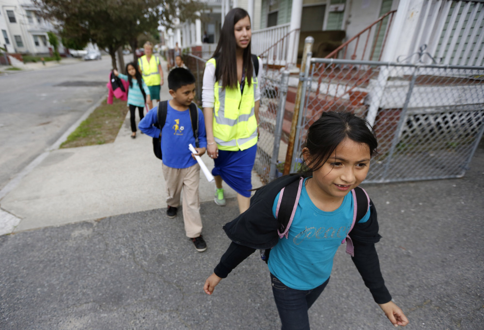 Children walk home from school escorted by Allyson Trenteseaux, center right. a Walking School Bus program manager, in Providence, R.I. The program is seen as a way to get kids active, fight childhood obesity and cut absenteeism.