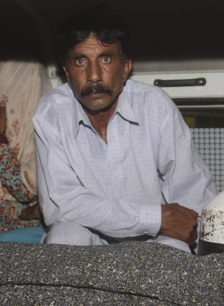 Mohammad Iqbal sits in an ambulance Tuesday with the body of his wife, stoning victim Farzana Parveen, 25.