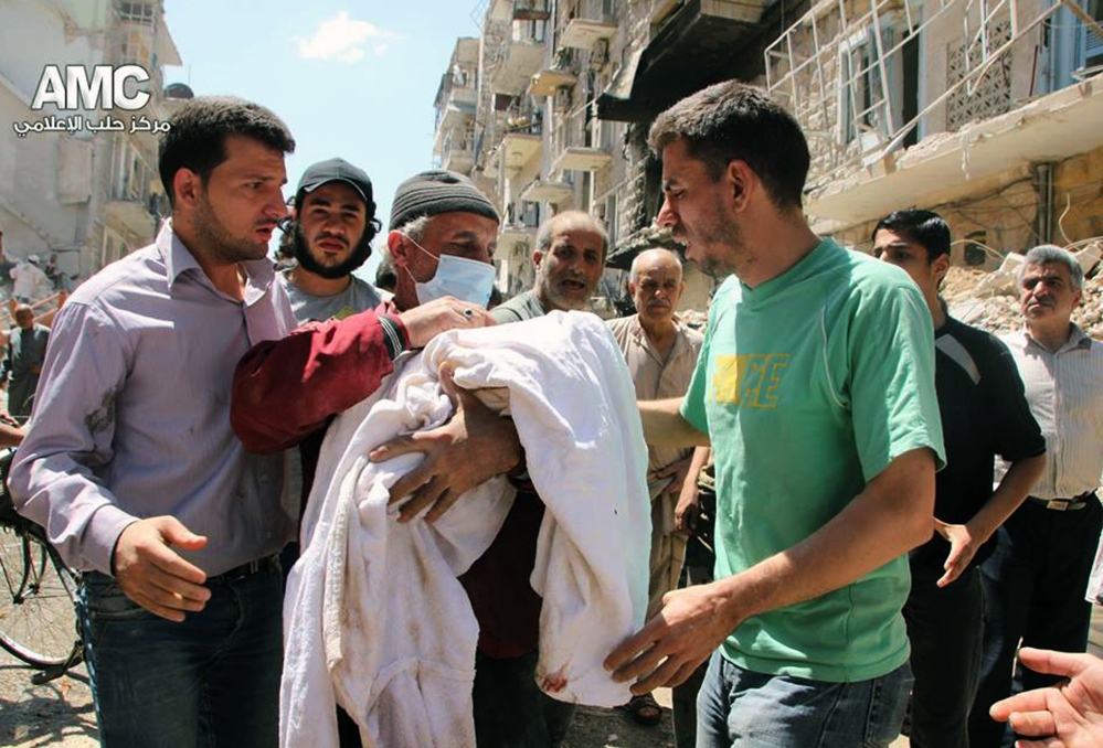 In this photo provided by the anti-government activist group Aleppo Media Center, which has been authenticated based on its contents and other AP reporting, shows a Syrian man, center, carrying the body of a victim of a Syrian government airstrike, in Aleppo, on Monday.