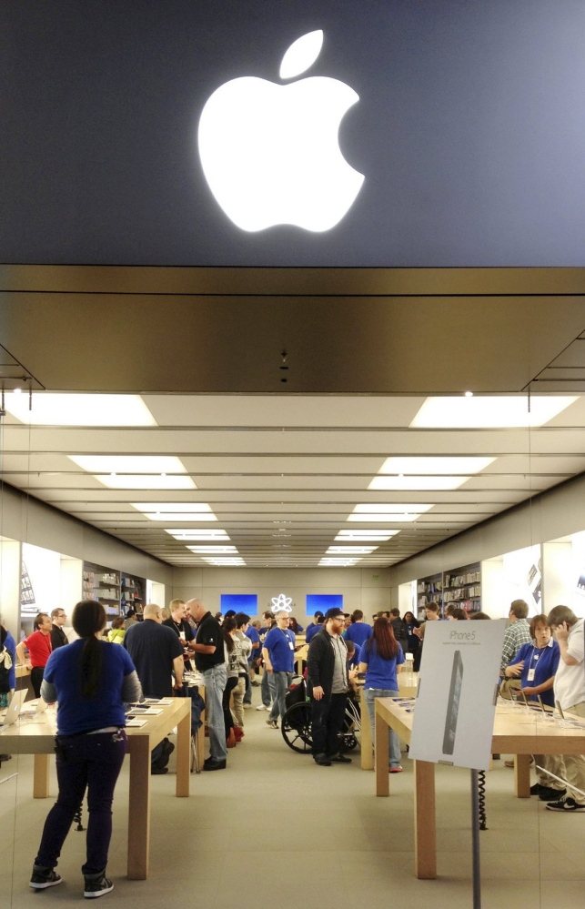 Apple employees, in blue shirts, work with customers at the Apple Store at the Maine Mall in South Portland. 2012 Press Herald file/Gregory Rec