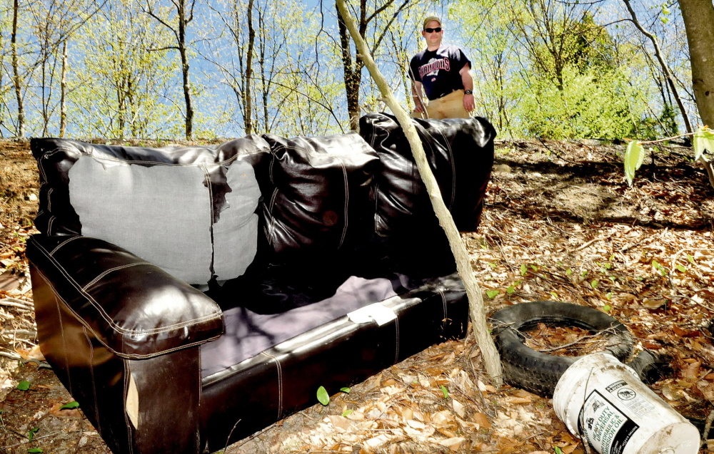 Gary Foss, facilities manager for the town of Belgrade, looks at trash including a couch, buckets and tires that were thrown in the woods off Penney Road in Belgrade. âThis is unnecessary and irresponsible,â Foss says. David Leaming/Morning Sentinel
