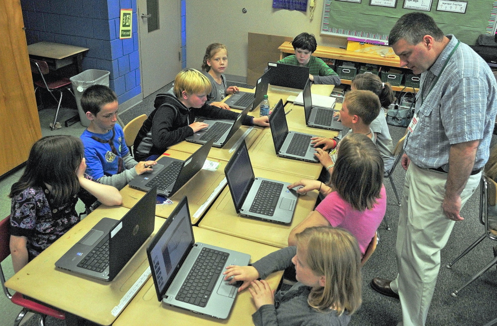 Tony Paine, CEO of Kepware Technologies, right, chats with students during a visit on Friday at Farrington Elementary School in Augusta. Paineâs company donated laptops to the classroom earlier in the year. Staff photo by Joe Phelan