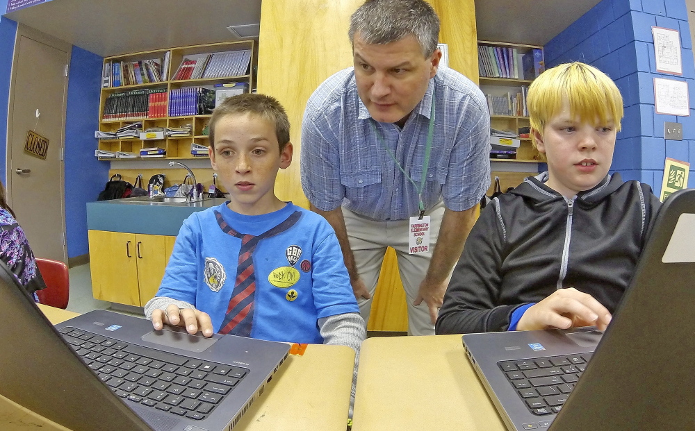 Tony Paine, CEO of Kepware Technologies, center, chats with fourth-graders Gabriel Biasuz, left, and Jared Barker about how they use the laptops that his company donated, on Friday at Farrington Elementary School in Augusta. Joe Phelan/Kennebec Journal