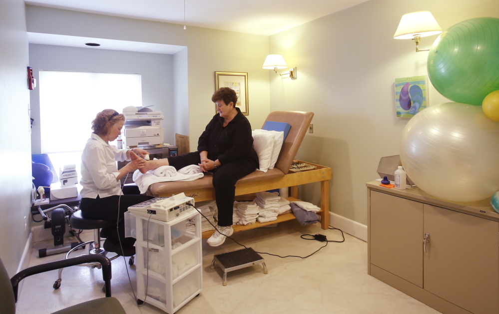 Patience M. Trainor, a physical therapist who lives on Vinalhaven, works on the foot of Doris Slivinsky at Islands Community Medical Services, the only health care facility on the island. In 2012, the clinic decided to stop recruiting doctors.
