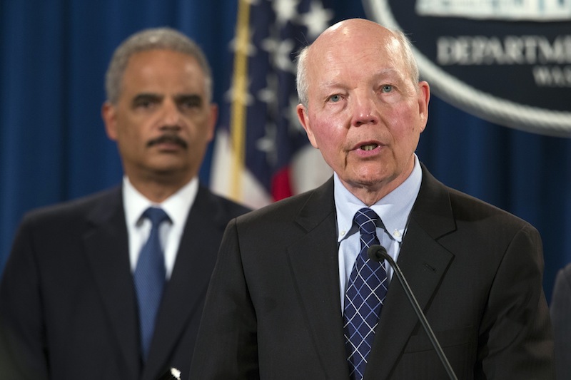 Attorney General Eric Holder, left, listens as IRS Commissioner John Koskinen speaks during a news conference at the Justice Department on Monday in Washington. The Justice Department charged Credit Suisse AG with helping wealthy Americans avoid paying taxes through offshore accounts.