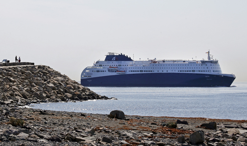 Two people watch the Nova Star cruise ferry make its way into Boston Harbor on Monday. The ferry will begin daily round trips between Portland and Nova Scotia on Thursday.
