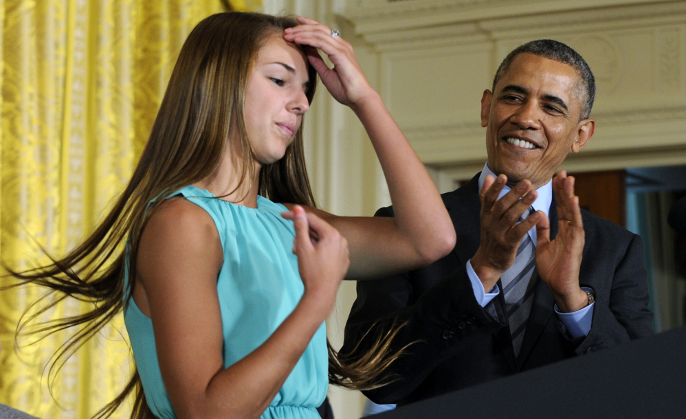 President Barack Obama applauds Victoria Bellucci, a 2014 graduate of Huntingtown High School in Huntingtown, Md., at a White House youth sports concussion summit Thursday. Bellucci suffered five concussions while playing high school and club soccer. The Associated Press