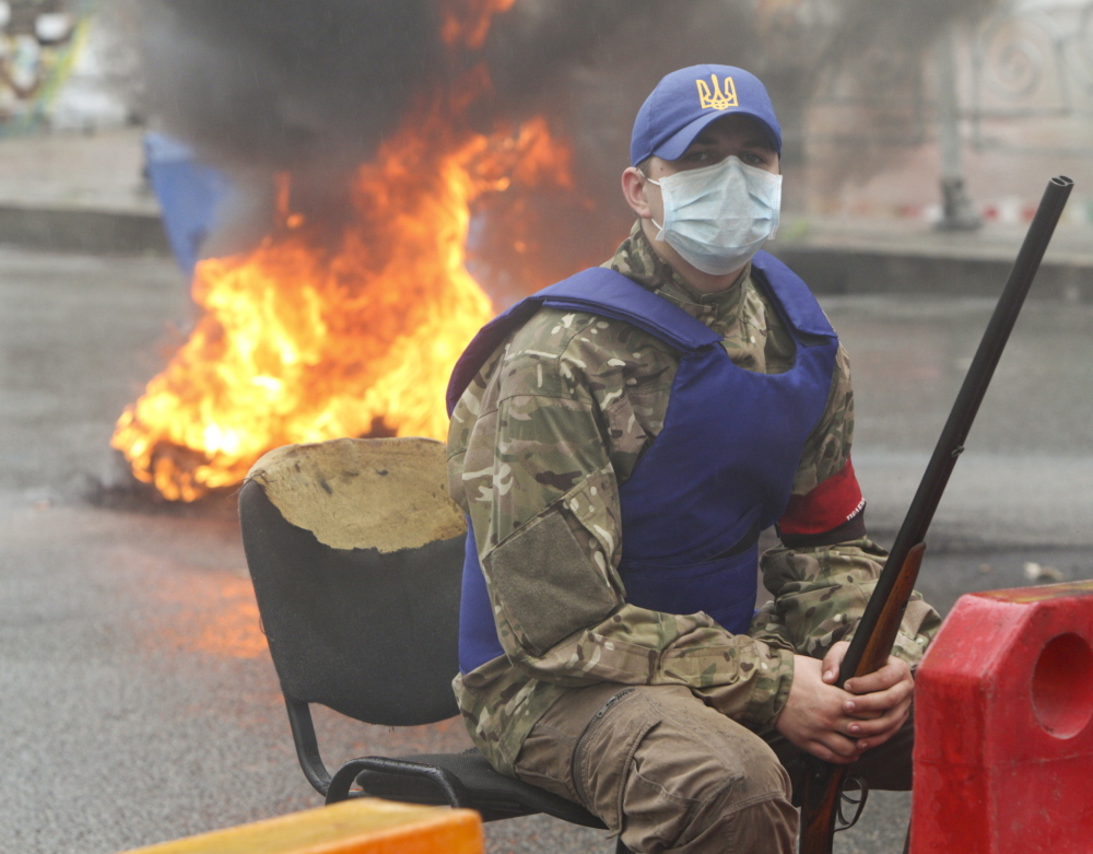 An activist sits near burning tires on Saturday in Independence Square in Kiev, Ukraine. Reuters