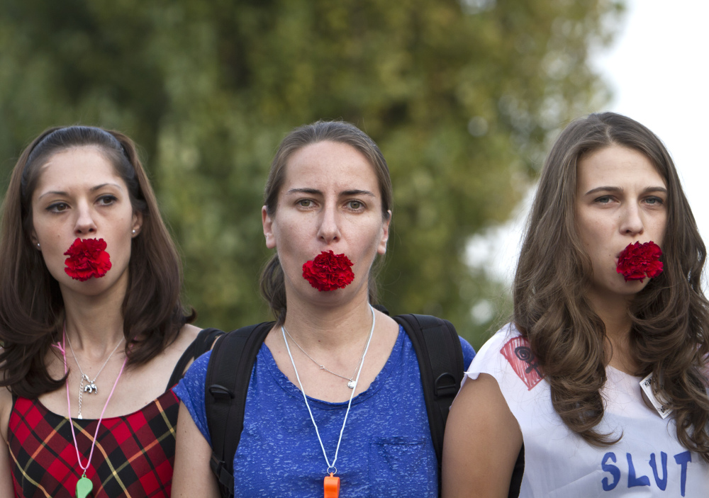 Activists hold carnations in their mouths during the a protest against harassment of women based on how they dress, in Bucharest, Romania, in October 2011. The Associated Press