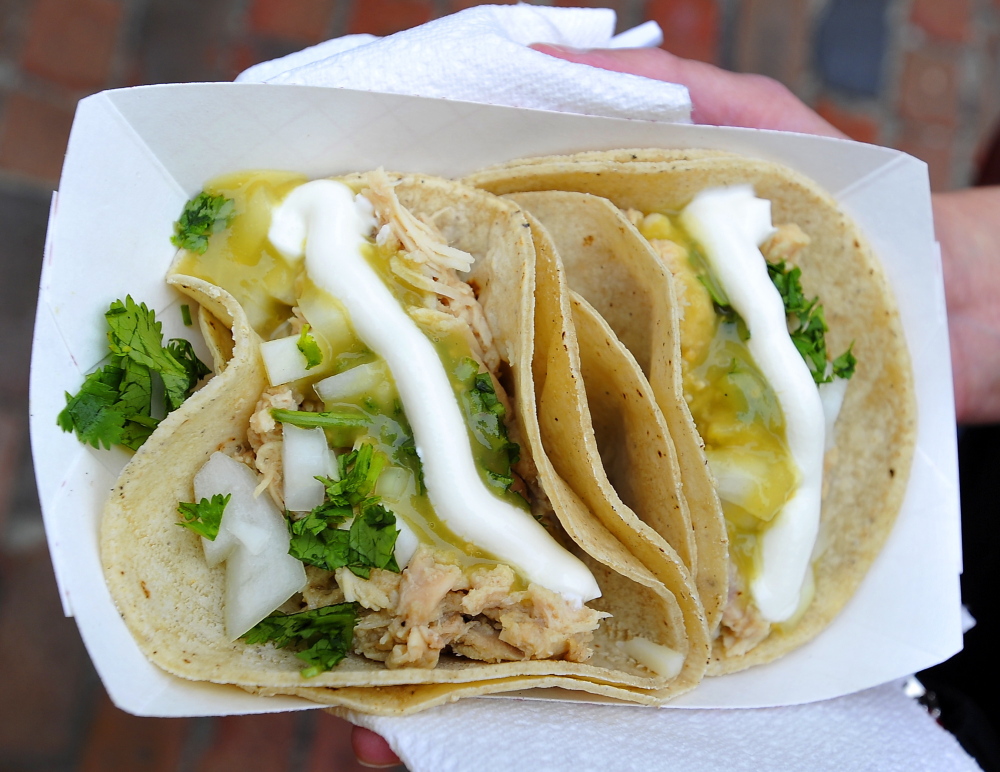 One of the many choices of tacos offered, two carnitas made with warm soft corn shells with chicken, cilantro, onions, cheese and sour cream.