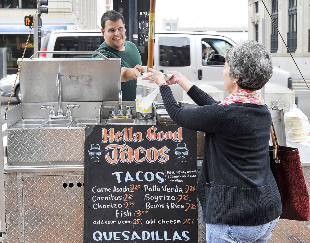 Hella Good Tacos cart dishing up on Monument Square. Cart manager Alexander Herzog hands a completed order of carnitos to Emily Levine from Brunswick. Photos by Gordon Chibroski/Staff Photographer