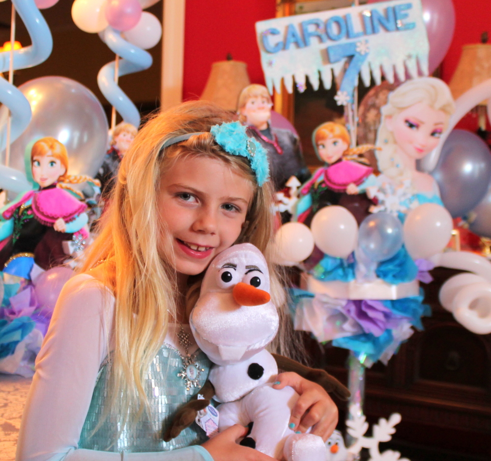 In a photo provided by her mother, Caroline Calder holds a stuffed snowman named Olaf, a character in “Frozen,” at her birthday party in May, and wears a hard-to-find dress based on princess attire in the film. The Associated Press