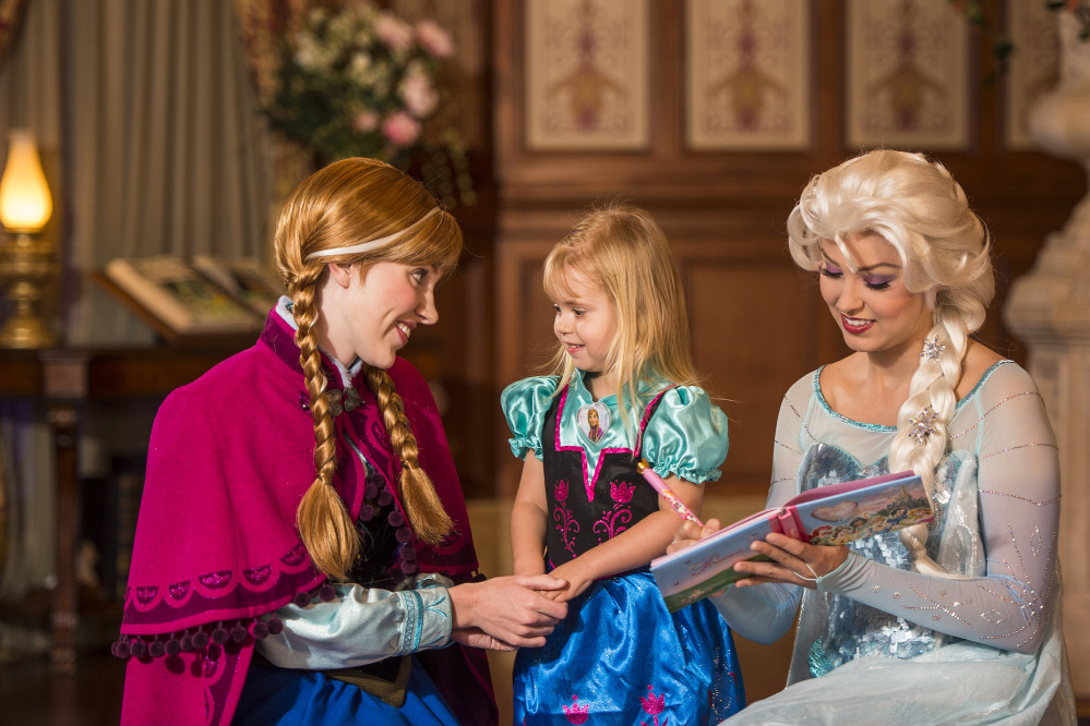 Disney characters playing princesses from the animated movie “Frozen,” Anna, left, and her sister Elsa, right, talk with a young fan at Walt Disney World Resort in Lake Buena Vista, Fla. Wait times to meet the sisters stretches for hours and reservations are snapped up quickly. The Associated Press