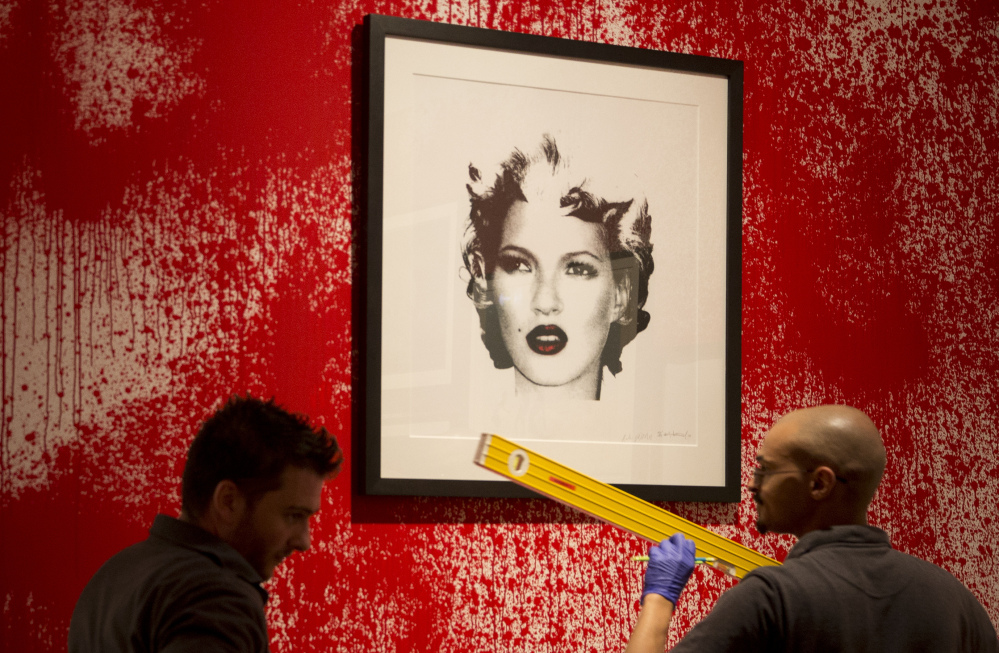 Sotheby’s employees organize Banksy art Friday during a preview of an "unauthorized retrospective" in London. The Associated Press 