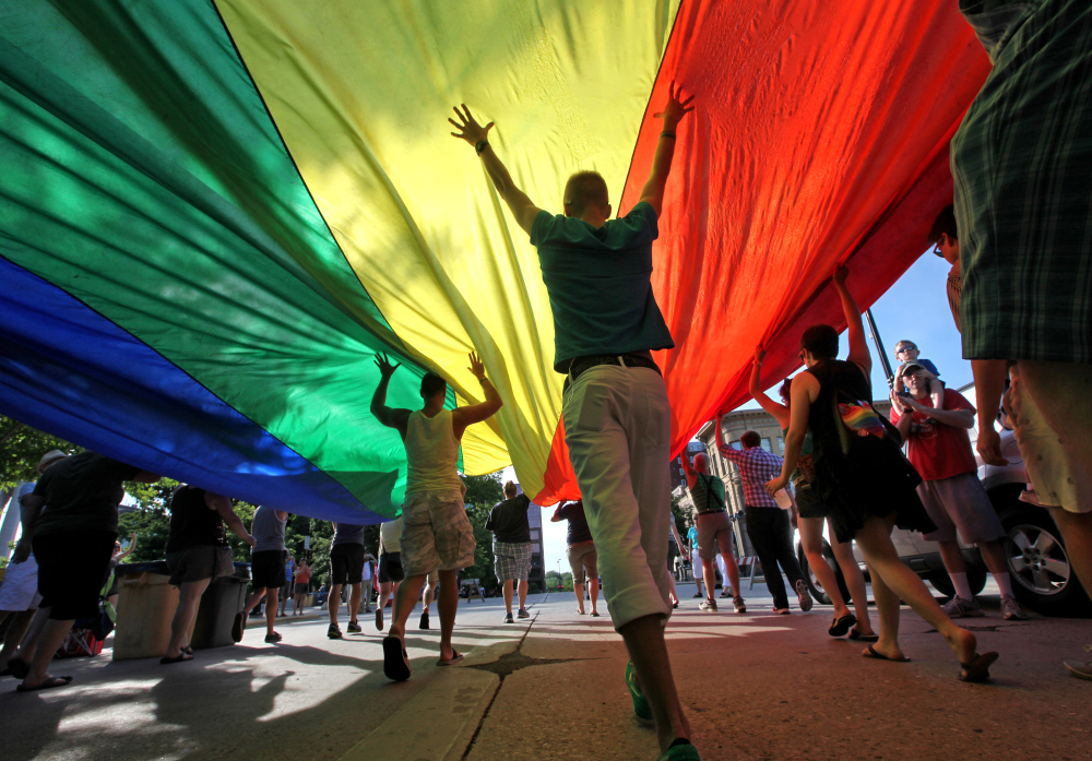 Supporters of a U.S. Supreme Court ruling  that overturned the federal Defense of Marriage Act carry a large rainbow flag during a parade around the Wisconsin State Capitol in Madison, Wis. A federal judge struck down Wisconsin’s ban on same-sex marriage Friday, ruling it unconstitutional. The Associated Press/Wisconsin State Journal