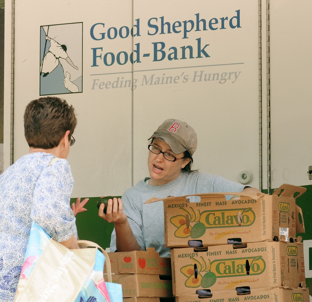 Jamee Luce talks to a client as she hands out avocados and tomatoes at the Good Shepherd Food-Bank’s Food Mobile in Augusta. The organization distributed a record amount of food in 2014.