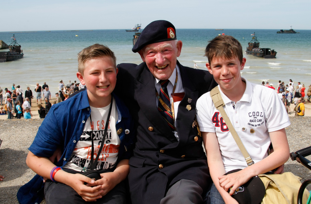 World War II veteran Reg Blake, 88, of London, who landed with the Royal Marines in Lion-sur-Mer on June 6, 1944, poses Friday with high school students Simon Legouge-Duval, left, and Adrien Sublin on the beach of Arromanches, France. The Associated Press 
