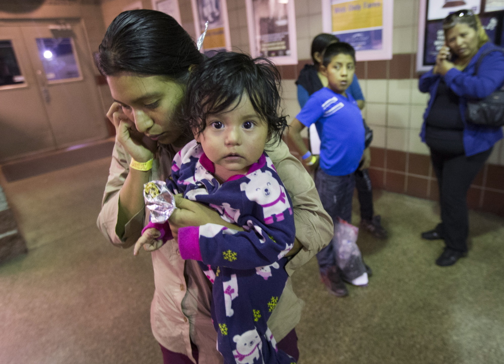 Judy Elizabeth Martinez of Guatemala holds her daughter Marjorie while calling family after being released at a Greyhound bus station in Phoenix by immigration officials on May 28. About 400 migrants were flown from Texas to Arizona on Memorial Day weekend. The Associated Press 