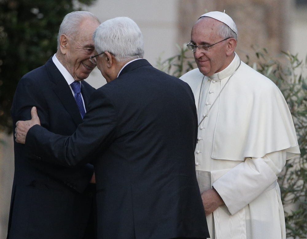 Pope Francis looks as Israel’s President Shimon Peres, left, and Palestinian President Mahmoud Abbas embrace during an evening of peace prayers in the Vatican gardens on Sunday. The Associated Press 