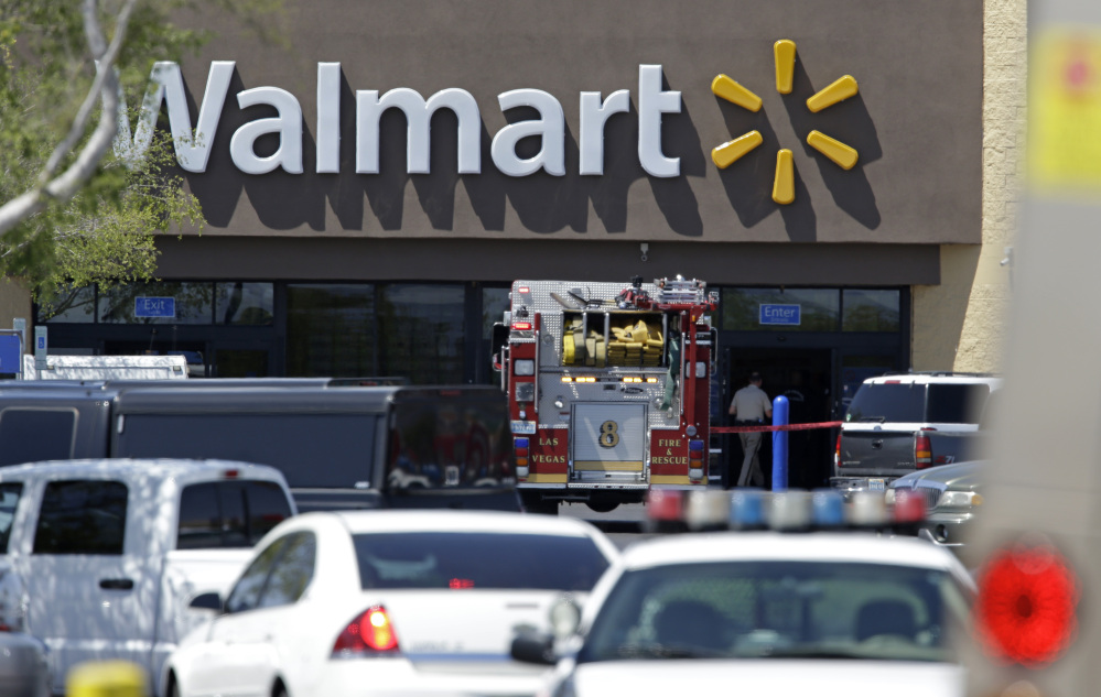 Police and firefighters appear on the scene of a shooting at a Wal-Mart on Sunday in Las Vegas. Police say two suspects shot two officers at a Las Vegas pizza parlor before fatally shooting a person and turning the guns on themselves at a nearby Walmart. The Associated Press