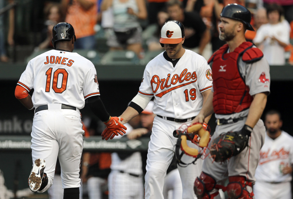 The Associated Press/Patrick Semansky Baltimore Orioles’ Adam Jones, left, is greeted by teammate Chris Davis in front of Boston Red Sox catcher David Ross, right, after Jones hit a solo home run in the first inning.