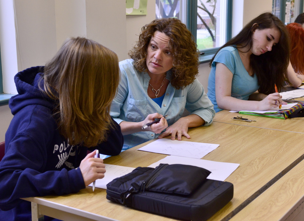 Deb Downing assists Emma Gaul, left, and Cheyenne Rowe with math homework at Poland Regional High School, which has had a proficiency-based program for 13 years. Logan Werlinger/Staff Photographer