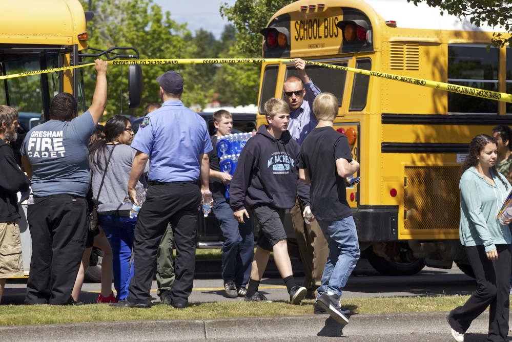 Students arrive by bus at the Fred Meyer grocery store parking lot in Wood Village, Ore., after a shooting at Reynolds High School on Tuesday.