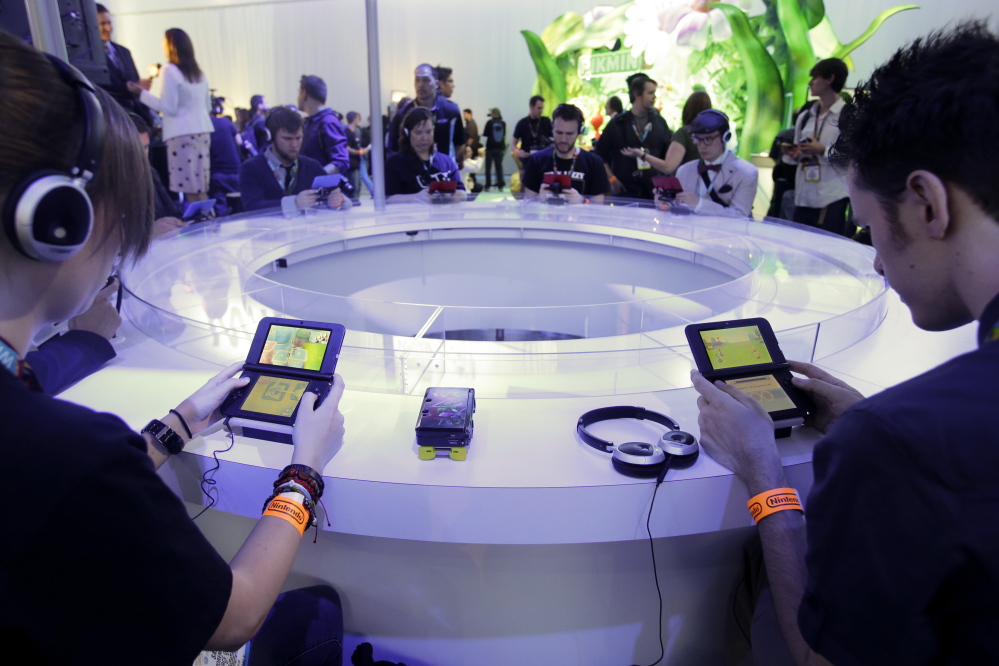 Players try out Nintendo games during an expo in Los Angeles. Nintendo on Tuesday announced that it is introducing a line of toy figures that interact with its games.