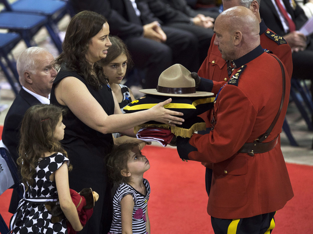 Nadine Larche, left, with her daughters Mia, Lauren and Alexa, receives the Canadian flag, and the Stetson and medals belonging to her husband, Constable Douglas James Larche, by Royal Canadian Mounted Police Commissioner Bob Paulson during the regimental funeral for Larche and two other officers at the Moncton Coliseum in Moncton, New Brunswick, on Tuesday, June 10, 2014. Constables David Ross, Fabrice Georges Gevaudan and Larche were killed in a shooting spree last Wednesday. Justin Bourque, 24, is facing three charges of first-degree murder and two charges of attempted murder. (AP Photo/The Canadian Press, Andrew Vaughan)