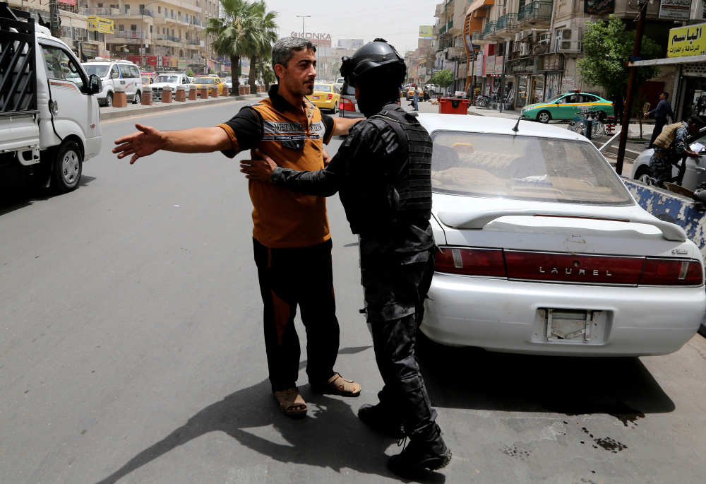 The Associated Press An Iraqi federal policeman searches a man at a checkpoint in Baghdad, Iraq, Wednesday. The Iraqi government has tightened security after a stunning assault in Mosul that exposed Iraq’s eroding central authority.