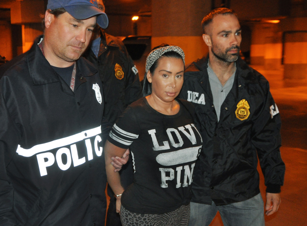 In this photo provided by the Drug Enforcement Administration, Samantha Barbash, is escorted by law enforcement officers following her arrest in New York. Barbash is allegedly part of a crew of New York City strippers who scammed wealthy men by drugging them and running up extravagant bills at topless clubs.