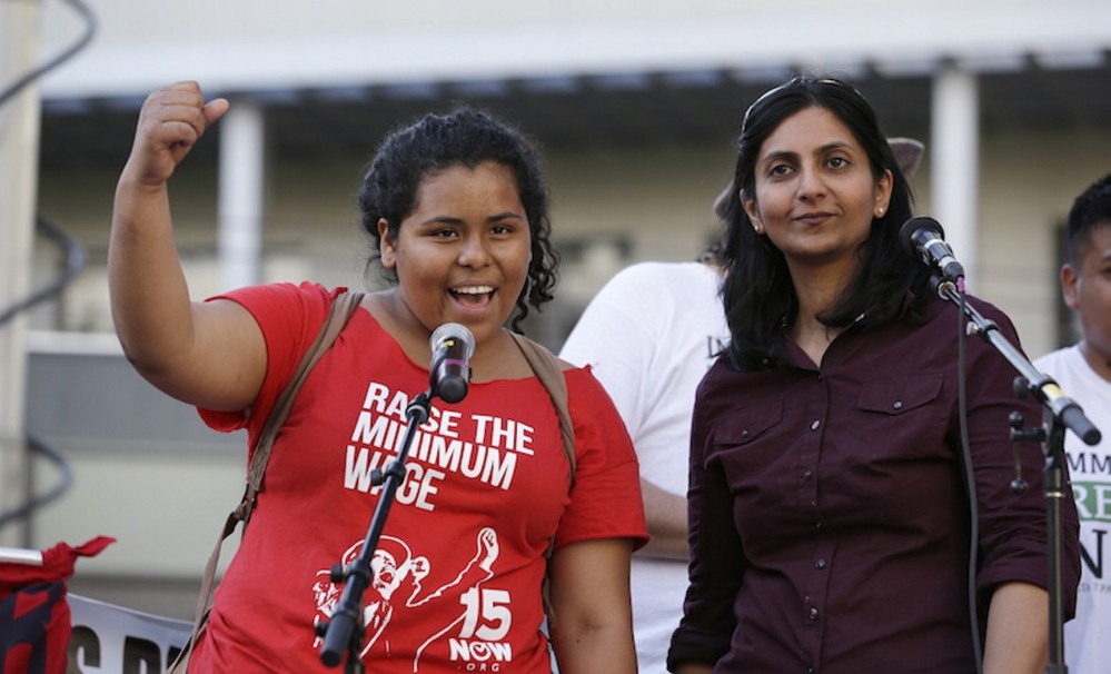 Stephanie Sucasaca holds up a fist at a rally in support of immigrant and workers rights and a boost in the minimum wage in Seattle on May 1. Seattle City Council Member Kshama Sawant is at right.