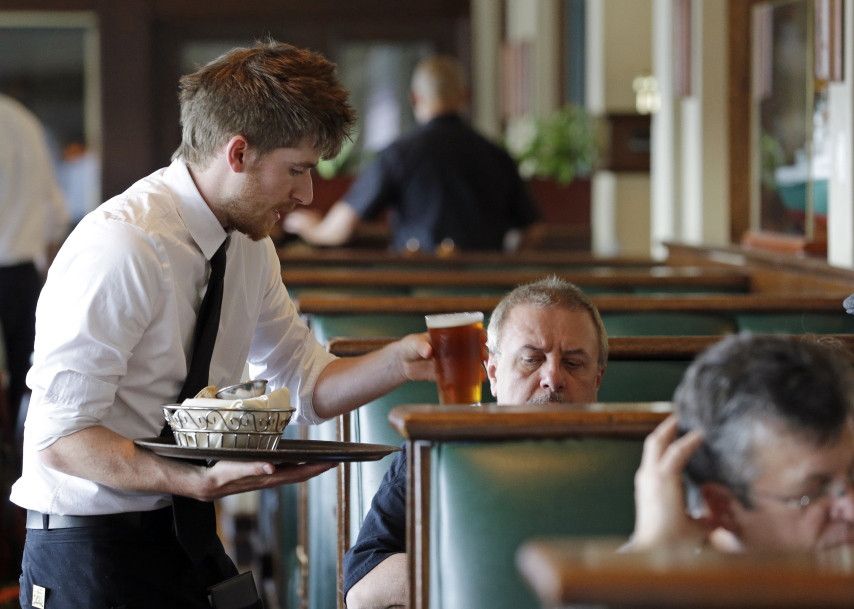 Waiter Spencer Meline serves a customer at Ivar’s Acres of Clams restaurant on the Seattle waterfront Wednesday, May 14, 2014. A federal lawsuit filed Wednesday challenges Seattle’s adoption of what would be the nation’s highest minimum wage as unfair to small franchises.