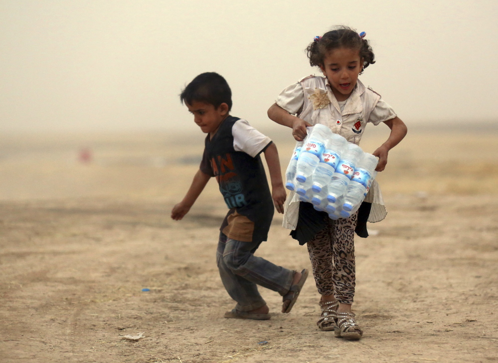 A girl who fled the violence in the Iraqi city of Mosul carries a case of water at a camp on the outskirts of Arbil in Iraq’s Kurdistan region on Thursday. Reuters