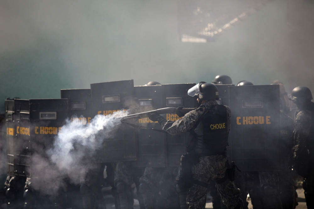 A Brazilian riot police aims at anti-World-Cup protester.