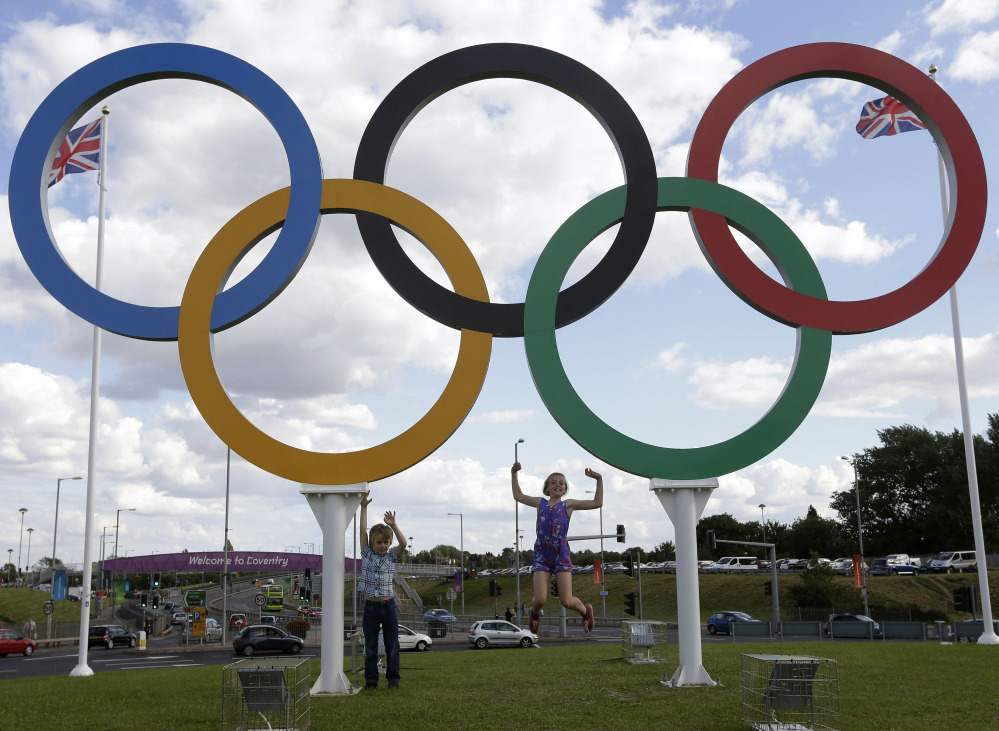In this July 28, 2012 file photo, British children pose for photos under a sculpture of the Olympics rings, in Coventry, England. Boston, Los Angeles, San Francisco and Washington are the cities still in the running for a possible U.S. bid to host the 2024 Summer Olympics.