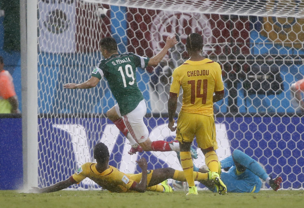 Mexico’s Oribe Peralta, centre, scores the opening goal during the group A World Cup soccer match between Mexico and Cameroon in the Arena das Dunas in Natal, Brazil, Friday, June 13, 2014.