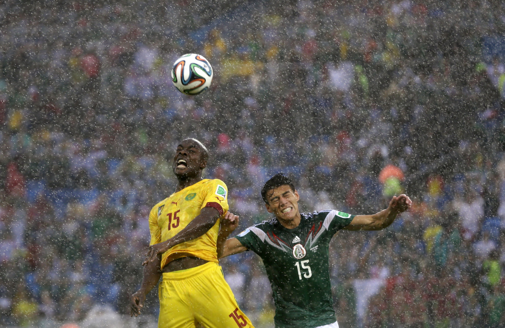 Cameroon’s Pierre Webo, left, and Mexico’s Hector Moreno battle for the ball  during the group A World Cup soccer match between Mexico and Cameroon in the Arena das Dunas in Natal, Brazil, Friday, June 13, 2014.