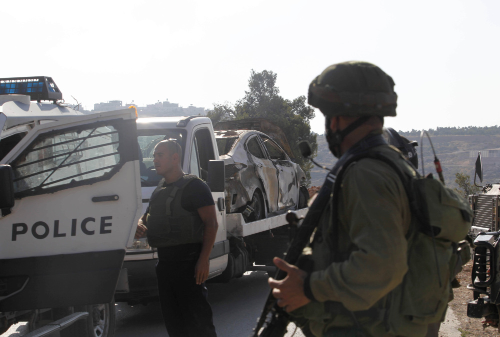 Israeli soldiers transport a burned-out car Friday that is reportedly connected to the disappearance of three teenage settlers near the West Bank city of Hebron. The three left their religious seminary Thursday night and have not been seen since.