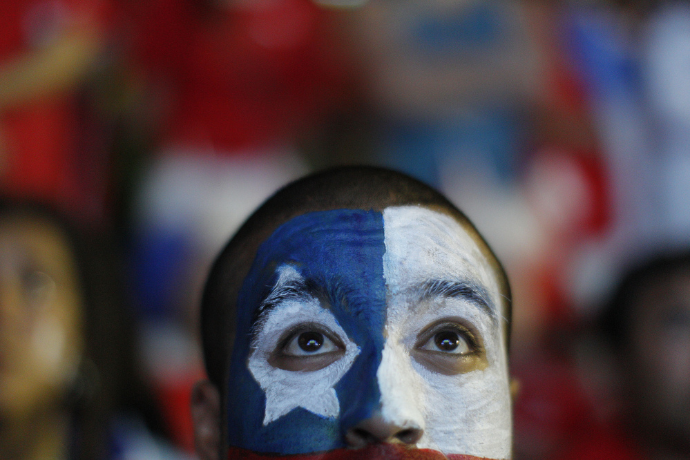 A soccer fan with his face painted to represent the Chilean national flag, watches the live broadcast of the World Cup match between Chile and Australia, inside the FIFA Fan Fest area on Copacabana beach in Rio de Janeiro, Brazil, Friday, June 13, 2014. Chile went on to defeat Australia 3-1 in the group B game at the Arena Pantanal in Cuiaba.