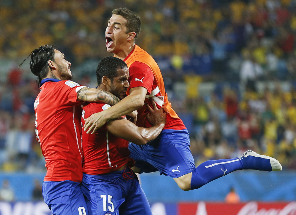 Chile’s Jean Beausejour, center, celebrates with teammates after scoring his side’s third goal during the group B World Cup soccer match between Chile and Australia in the Arena Pantanal in Cuiaba, Brazil, Friday, June 13, 2014.