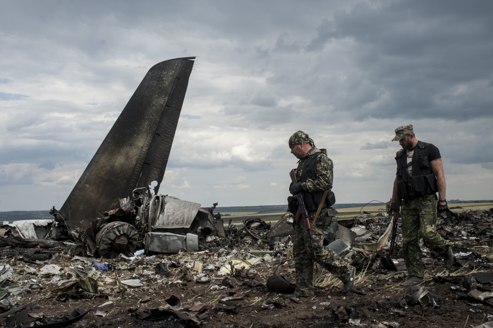 Pro-Russian fighters walk by the site of remnants of a downed Ukrainian army aircraft Il-76 at the airport near Luhansk, Ukraine, on Saturday. Pro-Russia separatists shot down a Ukrainian military transport plane Saturday, killing all 49 crew and troops aboard in a bloody escalation of the conflict in the country’s restive east.