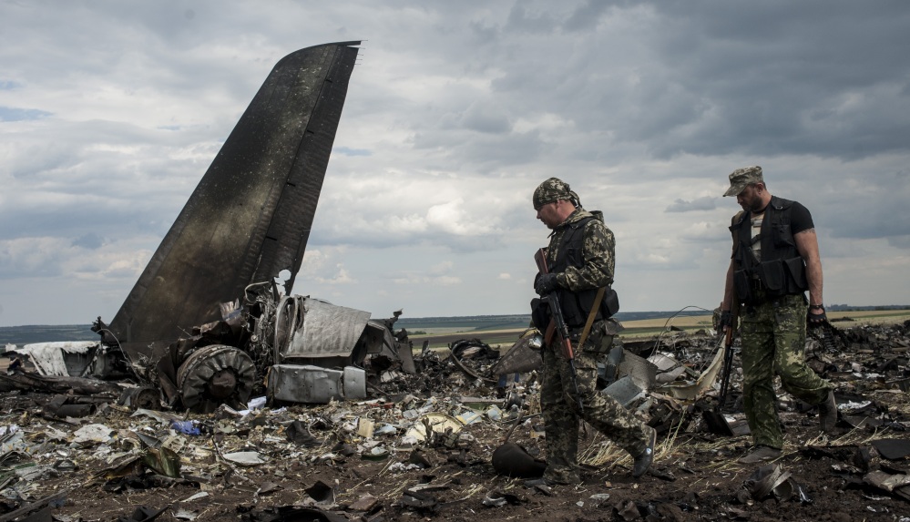 Pro-Russian fighters walk past the remains of a downed Ukrainian military transport plane at the airport near Luhansk, Ukraine, on Saturday. All 49 aboard were killed.