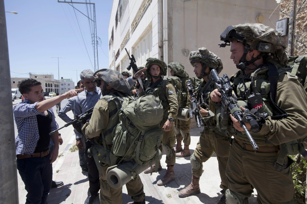 A Palestinian youth argues with Israeli soldiers as he tries to enter his home during a military operation to search for three missing teenagers outside the West Bank city of Hebron on Sunday.